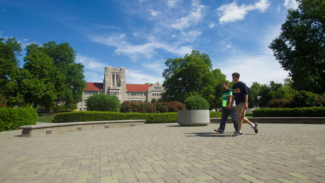 Two students walking across the front oval